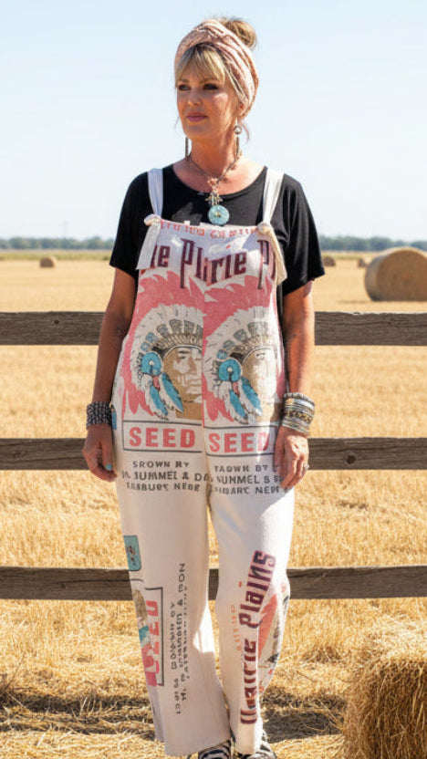 Person wearing a colorful 'Seed Seed' apron in a garden setting