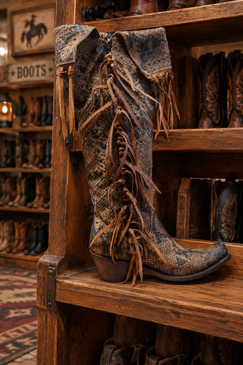 A tall western-style boot with a brown snakeskin pattern and long hanging fringe.
