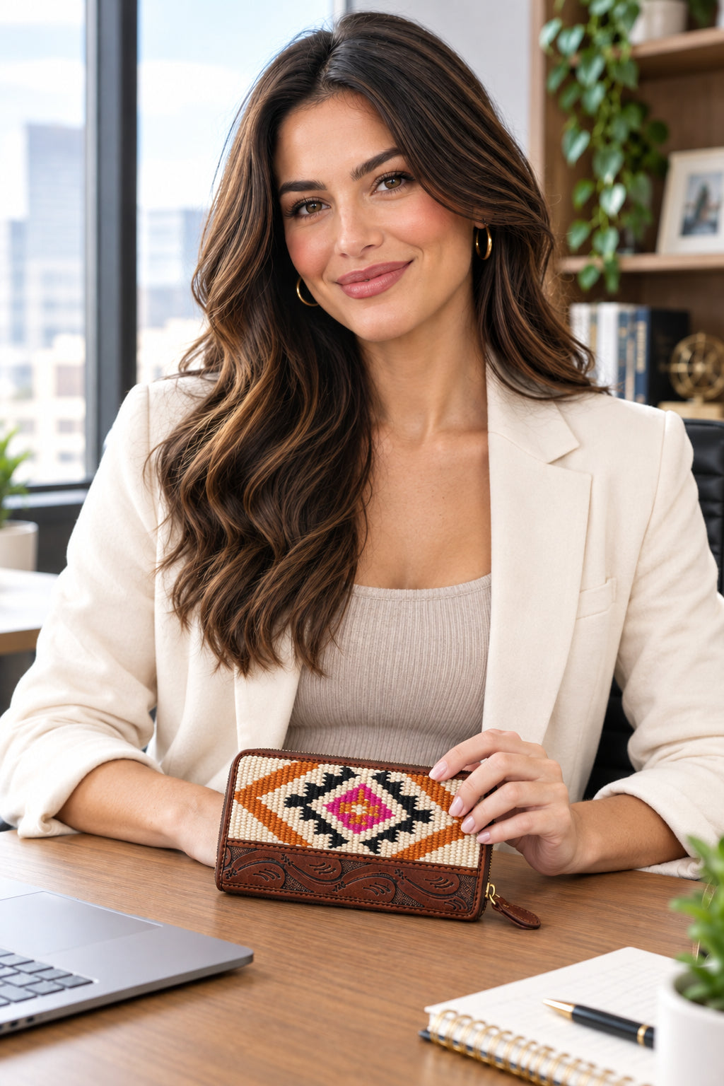 A zip-around wallet with a brown tooled leather lower section and a woven geometric upper section in cream, orange, black, and pink.
