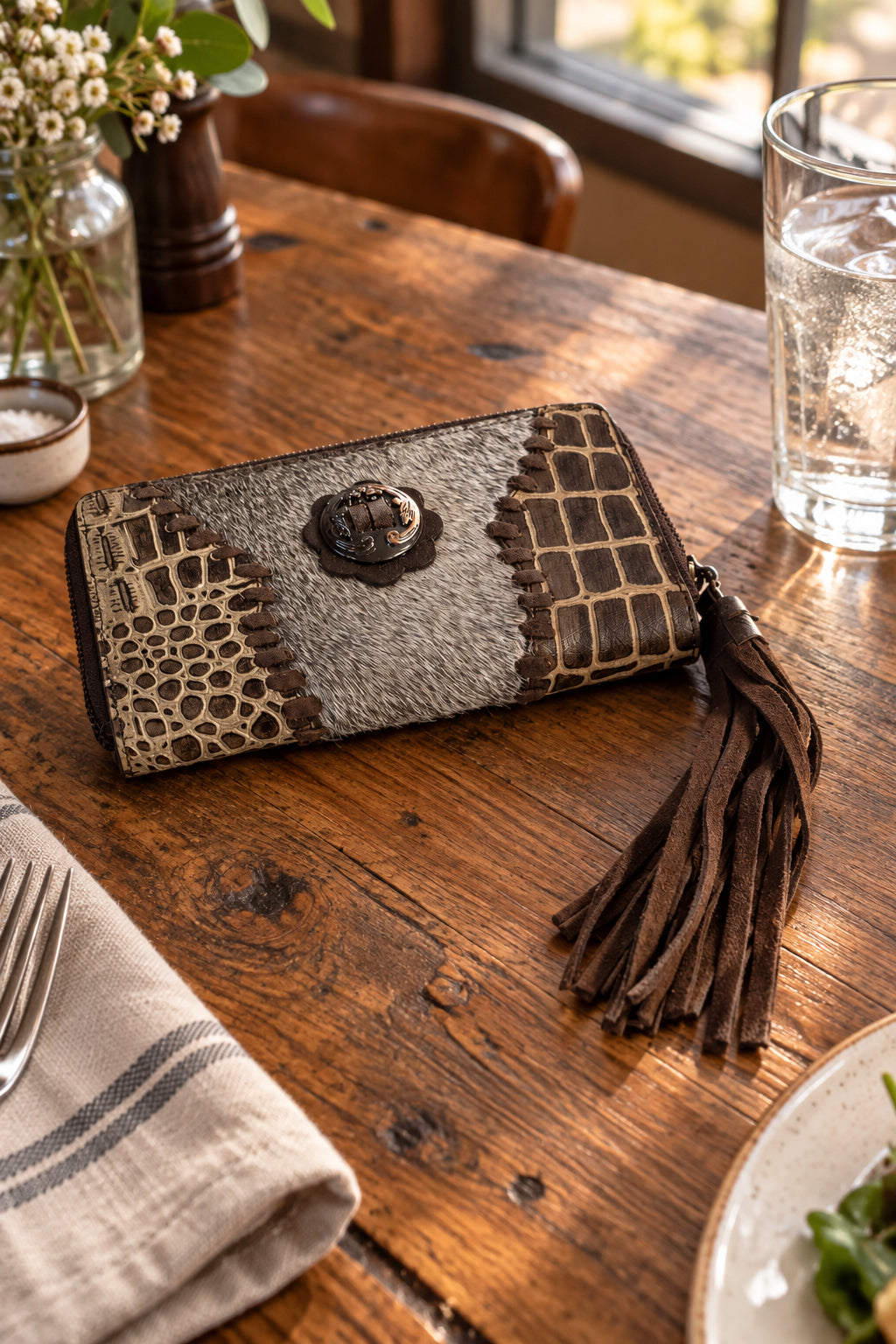 Crocodile print with whip stitched. Fringe tassel on zipper. Silver-toned medallion and leatherwork detail on front.
Multiple card slots on interior.