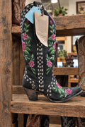 A black western cowboy boot with floral embroidery, studded detailing, and a dark wood heel.