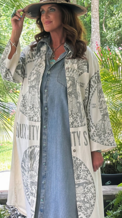 Woman in a garden wearing a long coat with newspaper print and patterned shoes.