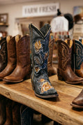 A western-style cowboy boot with dark blue leather and intricate gold, brown, and silver embroidery.