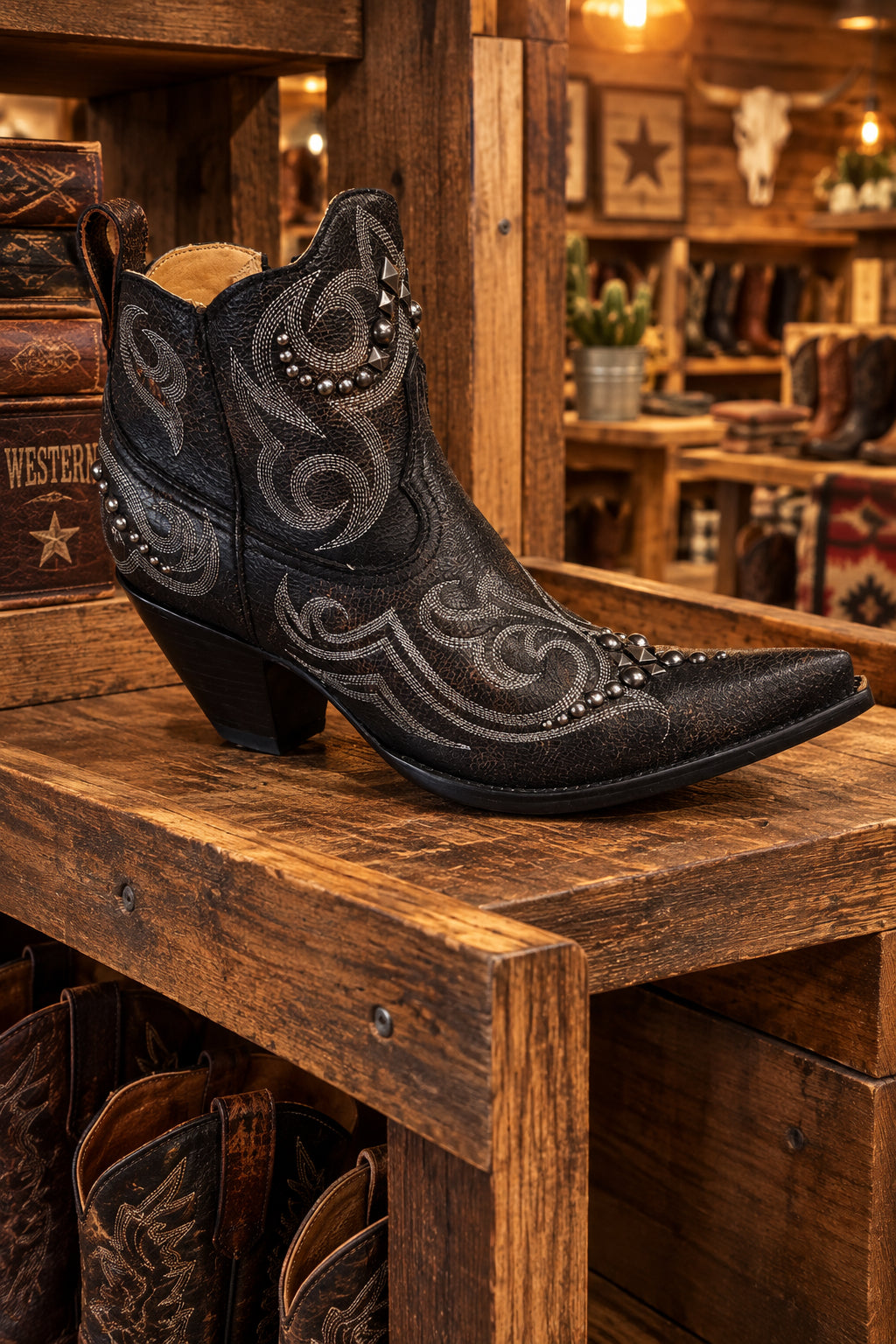 A black western-style boot with silver-toned embroidered swirls and studded details.